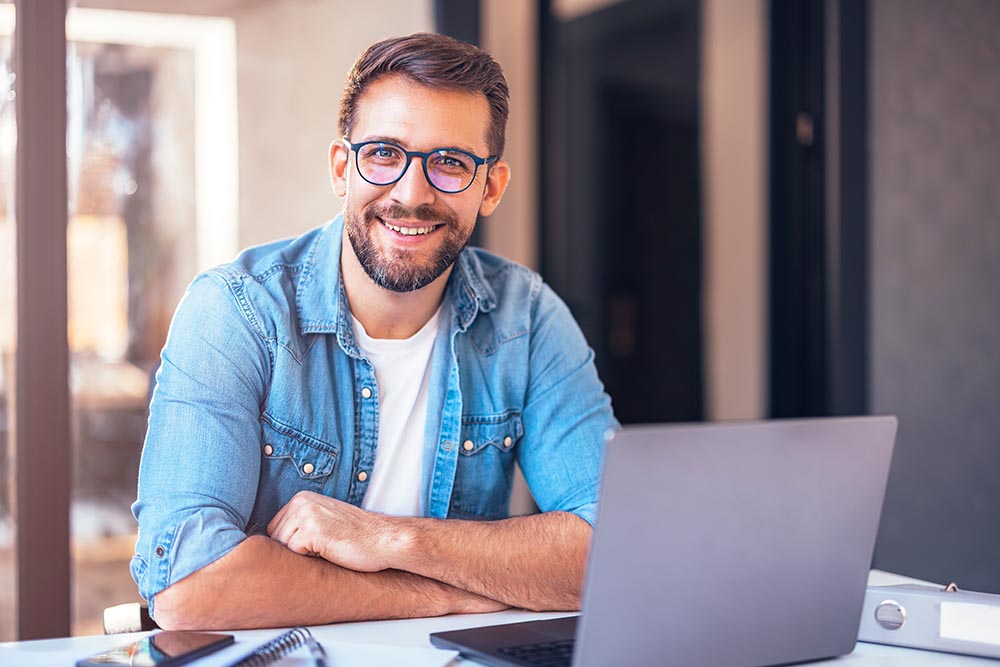 Portrait of attractive smiling man sitting in office and looking at camera.